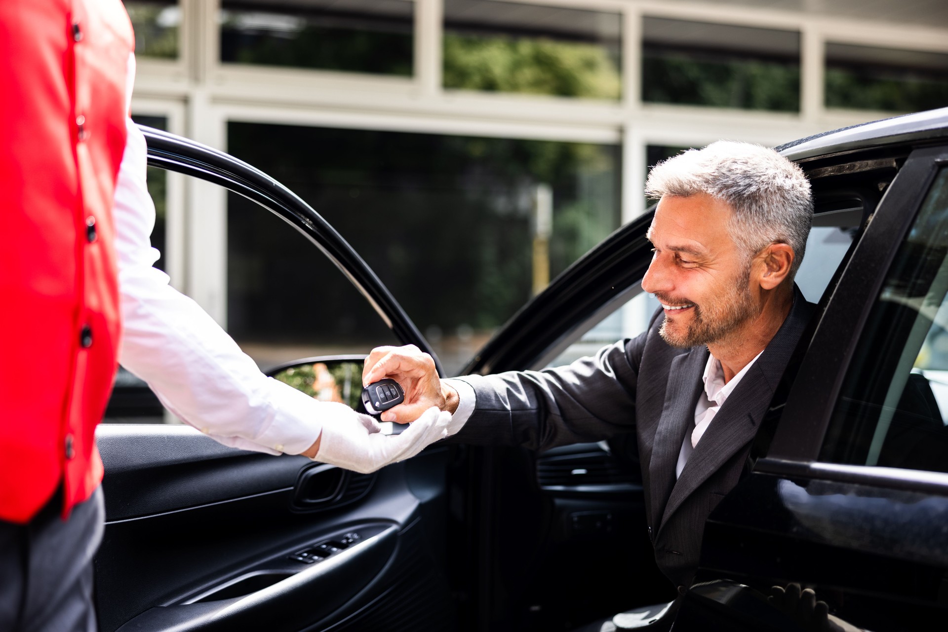 Businessperson handing car key to valet in hotel parking service